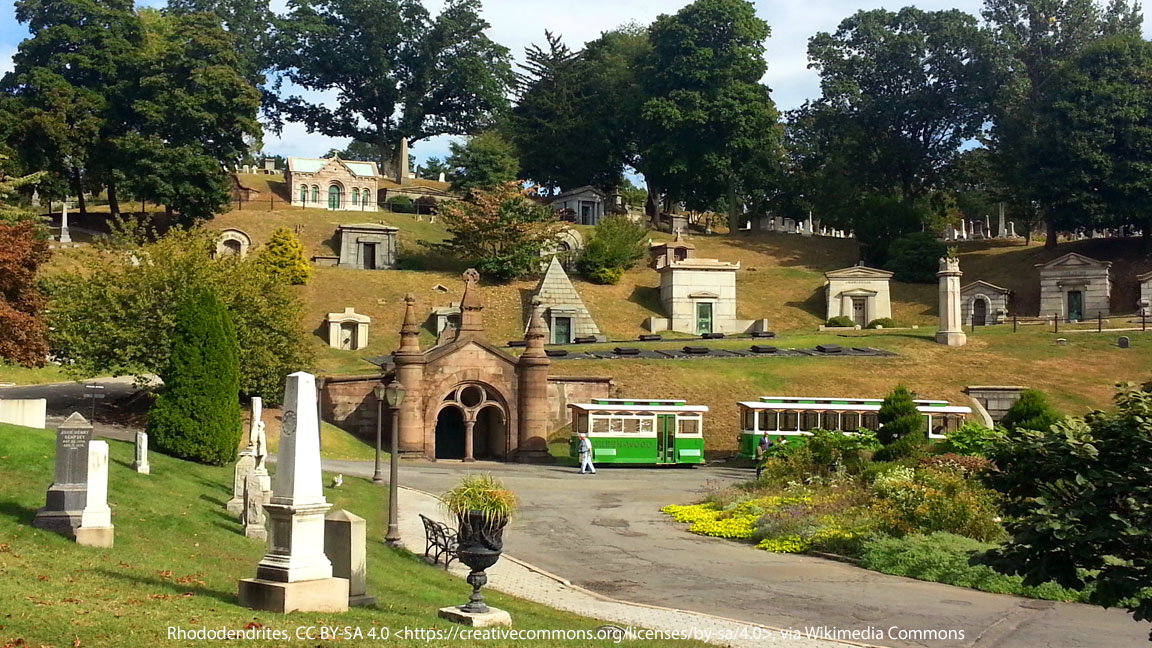 Tour bus at Green-Wood Cemetery with hillside mausoleums and historic monuments in view